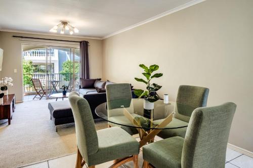 a living room with a glass table and chairs at Belina - Bougain Villas Premier in Cape Town