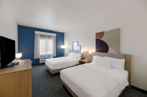 a hotel room with two beds and a flat screen tv at Spark by Hilton Midland South in Midland
