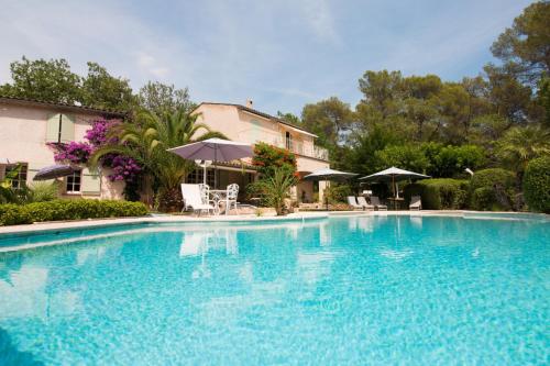 une grande piscine bleue avec chaises et parasols dans l'établissement Le bois des combes Cottage, à Lorgues