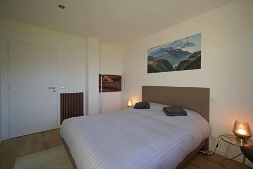 une chambre avec un lit blanc et un tableau au mur dans l'établissement Magnifique Suite Takapuna 4/6p vue lac & montagne, à Saint-Eustache