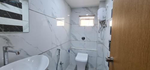 a white bathroom with a toilet and a sink at Hotel Vivan in Vadodara