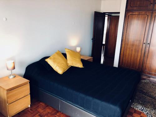 een slaapkamer met een blauw bed met 2 gele kussens bij Beautiful ocean view home in Paço de Arcos
