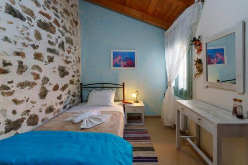 a bedroom with a bed and a stone wall at Petrino House Lasithi in Agios Georgios