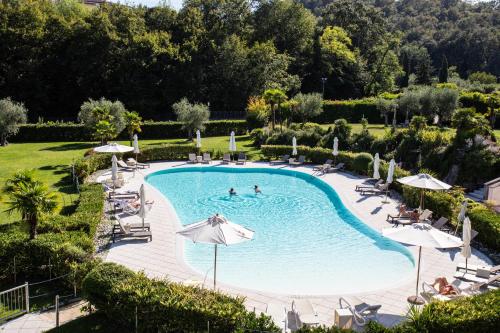 una piscina al aire libre con sillas y sombrillas en Monastero Resort & Spa - Garda Lake Collection, en Soiano del Lago