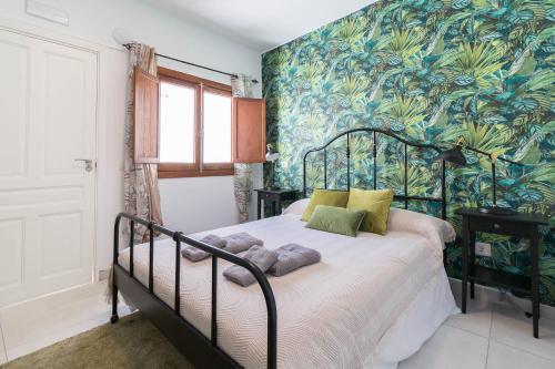 a bedroom with a bed with a tropical wallpaper at El Rincón de los Artistas in Las Palmas de Gran Canaria