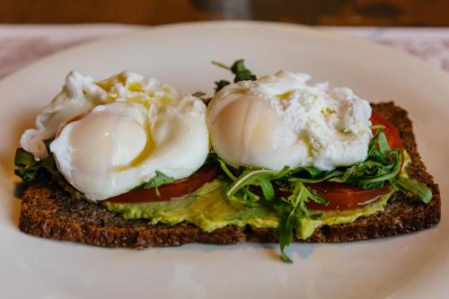 a sandwich with two poached eggs and tomatoes on a plate at Armerun Heritage Hotel & Residences in Šibenik