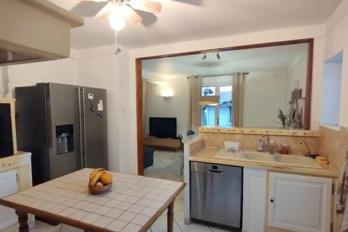 a kitchen with a table and a sink and a refrigerator at Jolie maison modulable de 4 à 6 lits avec jardinet in Irigny