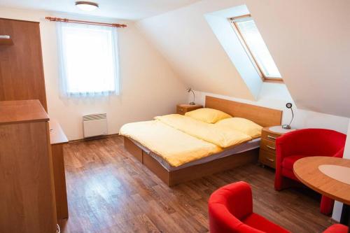 a bedroom with a bed and a red chair at Chaty Koloděje-modrý dům in Koloděje nad Lužnicí