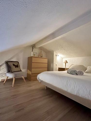 une chambre avec un lit blanc et une chaise dans l'établissement Appartement Duplex Forclaz, à Chamonix-Mont-Blanc