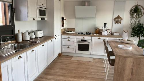 a kitchen with white cabinets and a wooden table at Rêverie en Périgord du Domaine des Hauts de Rouquette in Eymet