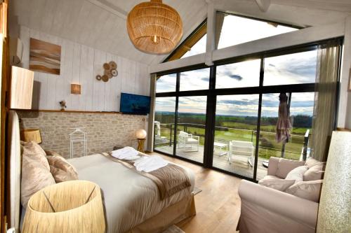 a bedroom with a bed and a couch and a large window at Rêverie en Périgord du Domaine des Hauts de Rouquette in Eymet