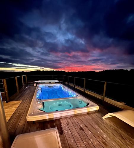 a hot tub on a deck at sunset at Rêverie en Périgord du Domaine des Hauts de Rouquette in Eymet