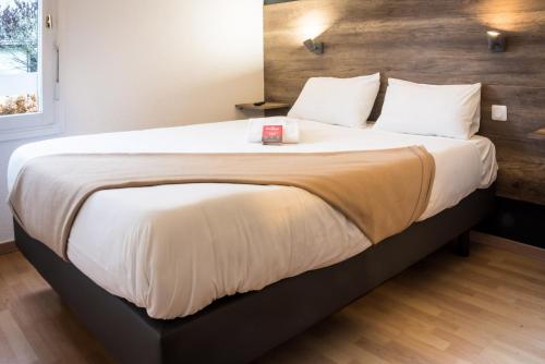 1 dormitorio con 1 cama grande con sábanas y almohadas blancas en Fasthôtel - Un hôtel FH Confort en Limoges
