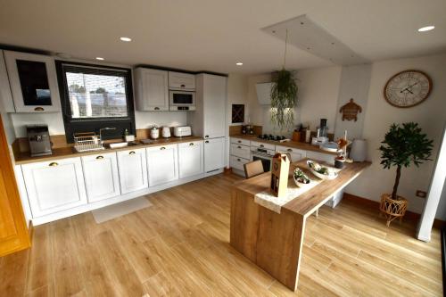 a large kitchen with white cabinets and a wooden floor at Rêverie en Périgord du Domaine des Hauts de Rouquette in Eymet