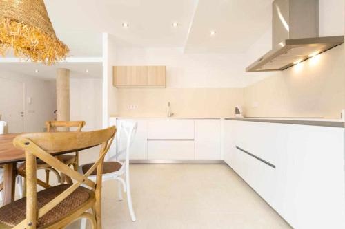 a kitchen with white cabinets and a table and chairs at Roses Casc Antic SL Sabater 5 in Roses