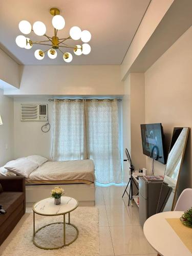 een slaapkamer met een bed en een televisie en een tafel bij The Olive Place in Manilla
