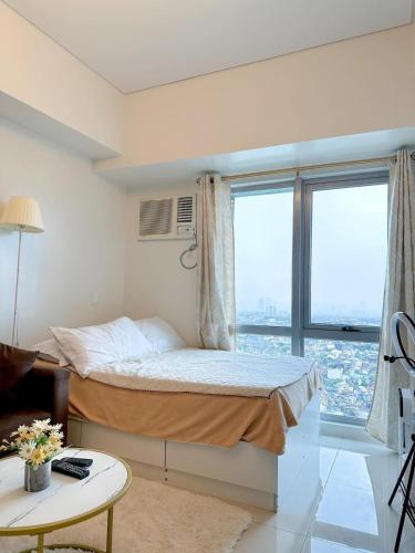 um quarto com uma cama e uma grande janela em The Olive Place em Manila