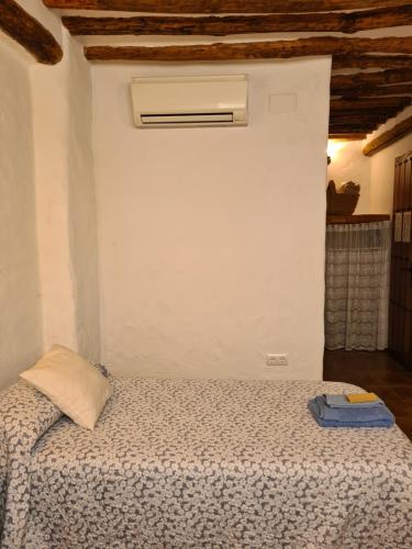 a bedroom with a bed with a white wall at La Posada Amena in Carcabuey