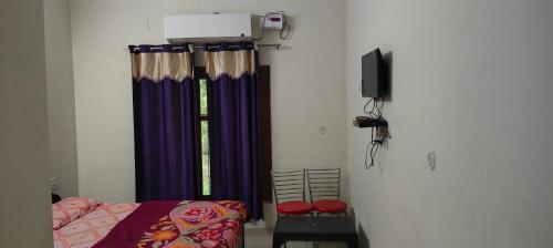 1 dormitorio con 1 cama y una ventana con cortinas moradas en Jagan Hotel And Restaurant en Bhara