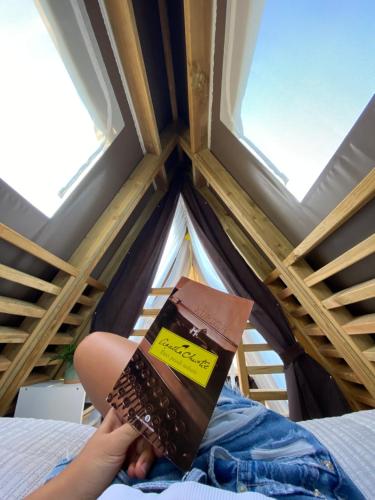 a person sitting on a bed reading a book at A-luxury Glamping by La Mignola in Fasano