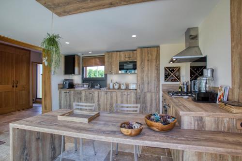 a kitchen with wooden cabinets and a large wooden table at L'Orée du Bois du Domaine des Hauts de Rouquette in Eymet