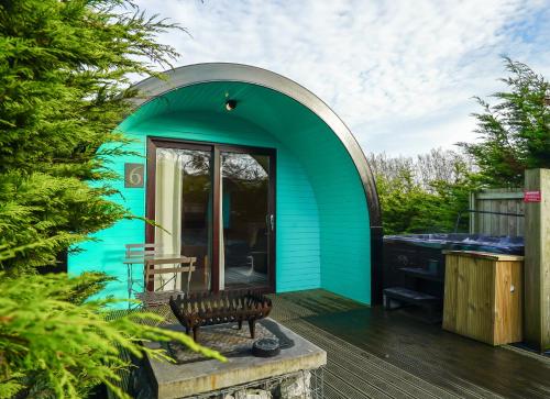 een groen tiny house met een houten terras bij Original Glamping Pod with Hot Tub in Frodsham
