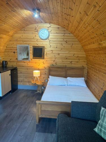 a bedroom with a bed and a clock on the wall at Original Glamping Pod with Hot Tub in Frodsham