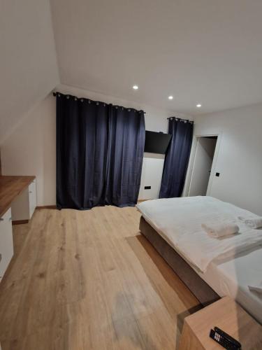 1 dormitorio con 1 cama grande y cortinas azules en Gorska Idila - Villa Lipa, en Stari Laz