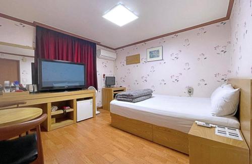 um quarto de hotel com uma cama e uma televisão de ecrã plano em Dongil Motel em Mokpo