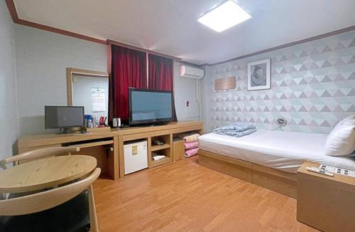 a bedroom with a bed and a desk with a television at Dongil Motel in Mokpo