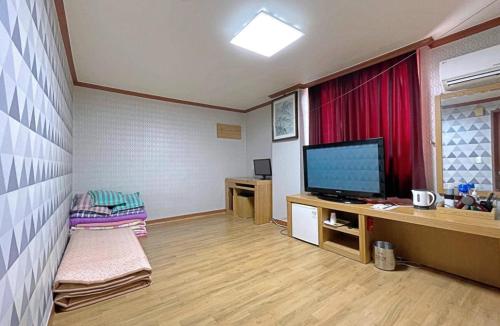 a living room with a flat screen tv and a desk at Dongil Motel in Mokpo