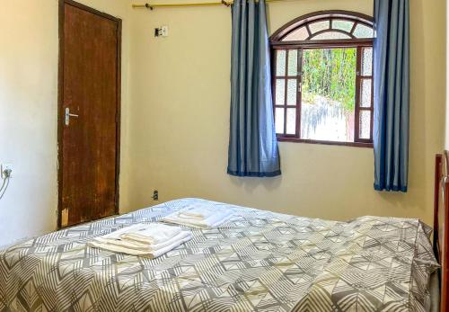 1 dormitorio con 1 cama con cortinas azules y ventana en Casa de campo c vista para a Lagoa de Saquarema RJ, en Saquarema