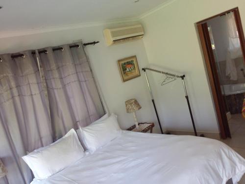 un letto con lenzuola e cuscini bianchi in una camera da letto di HLULALA GUEST HOUSE a Hluhluwe