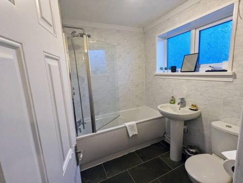 a bathroom with a tub and a sink and a toilet at The Cwtch Flat at The Lodge by Cefn Tilla in Usk