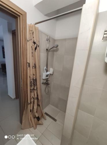 a bathroom with a shower with a shower curtain at Larnaca Bay Suites in Larnaka