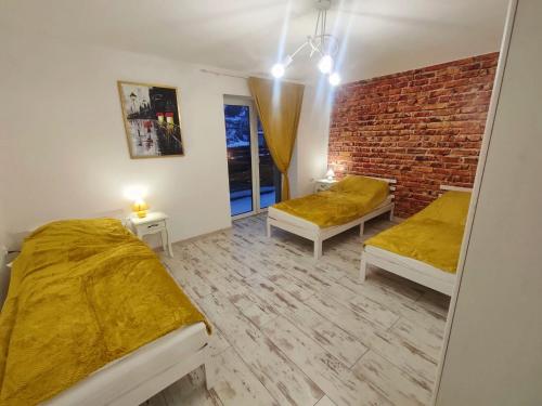 una camera con due letti e un muro di mattoni di Apartamenty na Maciejową a Rabka-Zdroj