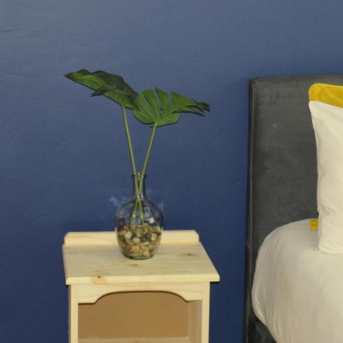 un jarrón con una planta en una mesa junto a una cama en 43 Home apartment en Del Judor