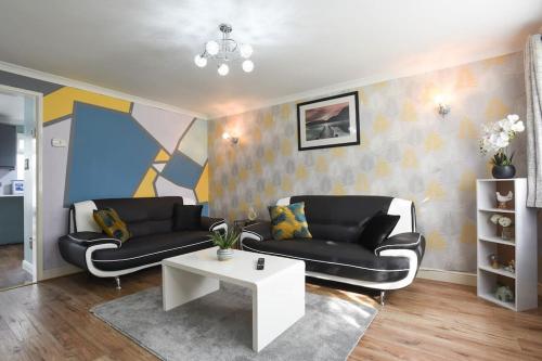 a living room with two black couches and a table at Spacious 4-Bed Family House in Portsmouth