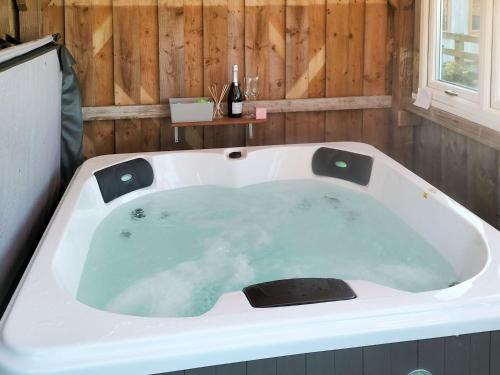 a bath tub in a bathroom with a bottle of wine at The Granary in North Kilvington