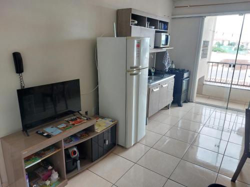 a kitchen with a white refrigerator and a table at Apto de 2 quartos com AR localizado no centro sul in Santo Ângelo