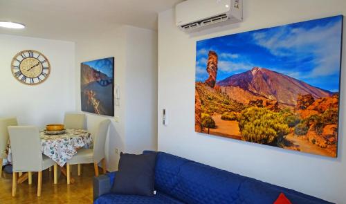 Piso en Candelaria con terraza, vistas al mar, aire acondicionado y garaje في كانديلاريا: غرفة معيشة مع أريكة زرقاء وطاولة
