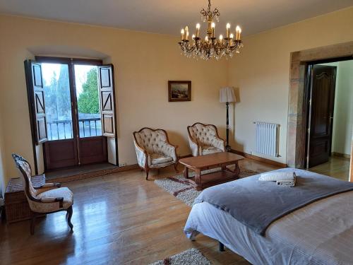 a bedroom with a bed and chairs and a chandelier at Palacio Marqués Vega de Anzo - Villa de campo sXVII in Siero