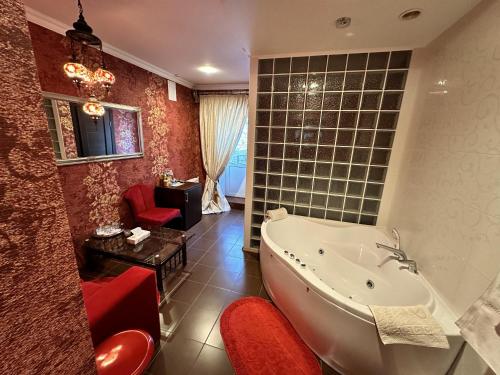 a bathroom with a tub and a chair and a table at Hotel Nika in Chornomorsk