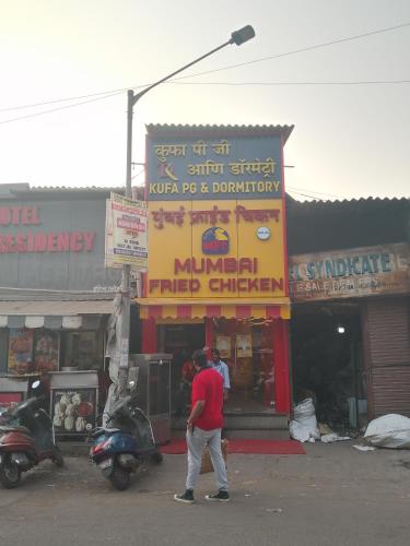 a man walking in front of a store with a scooter at Kufa PG Dormitory in Mumbai