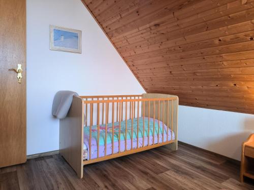 a crib in a room with a wooden ceiling at Ruthenberg in Kronsgaard- gemütliche Ferienwohnungen, 1700m vom Ostseestrand entfernt in Kronsgaard
