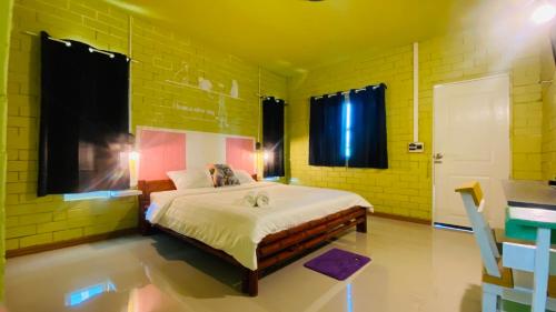 1 dormitorio con 1 cama grande en una habitación amarilla en พิมานอินทร์ รีสอร์ท, en Ban Phang Khwang Tai