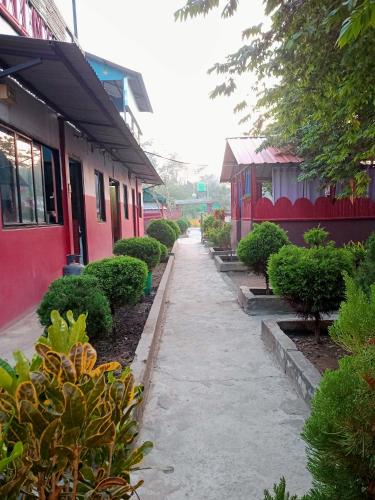 a walkway between two buildings with bushes and trees at Dreams restaurant and lodge in Maruwā Ghāt