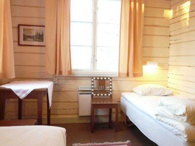 1 dormitorio con 2 camas, mesa y ventana en STF Kvikkjokk Fjällstation, en Kvikkjokks Kapell