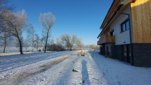 a snow covered road next to a building at Lipno Apartments BERGMAX, Ski Areál Lipno 16min dojezd - Resort Malé Lipno s terasou a zahrádkou, parking free in Černá v Pošumaví