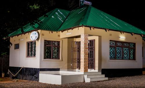 a small house with a green roof and a clock at Wangu Apartments in Livingstone